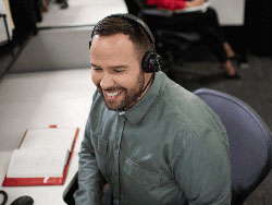 A person sitting in front of a computer with a headset on