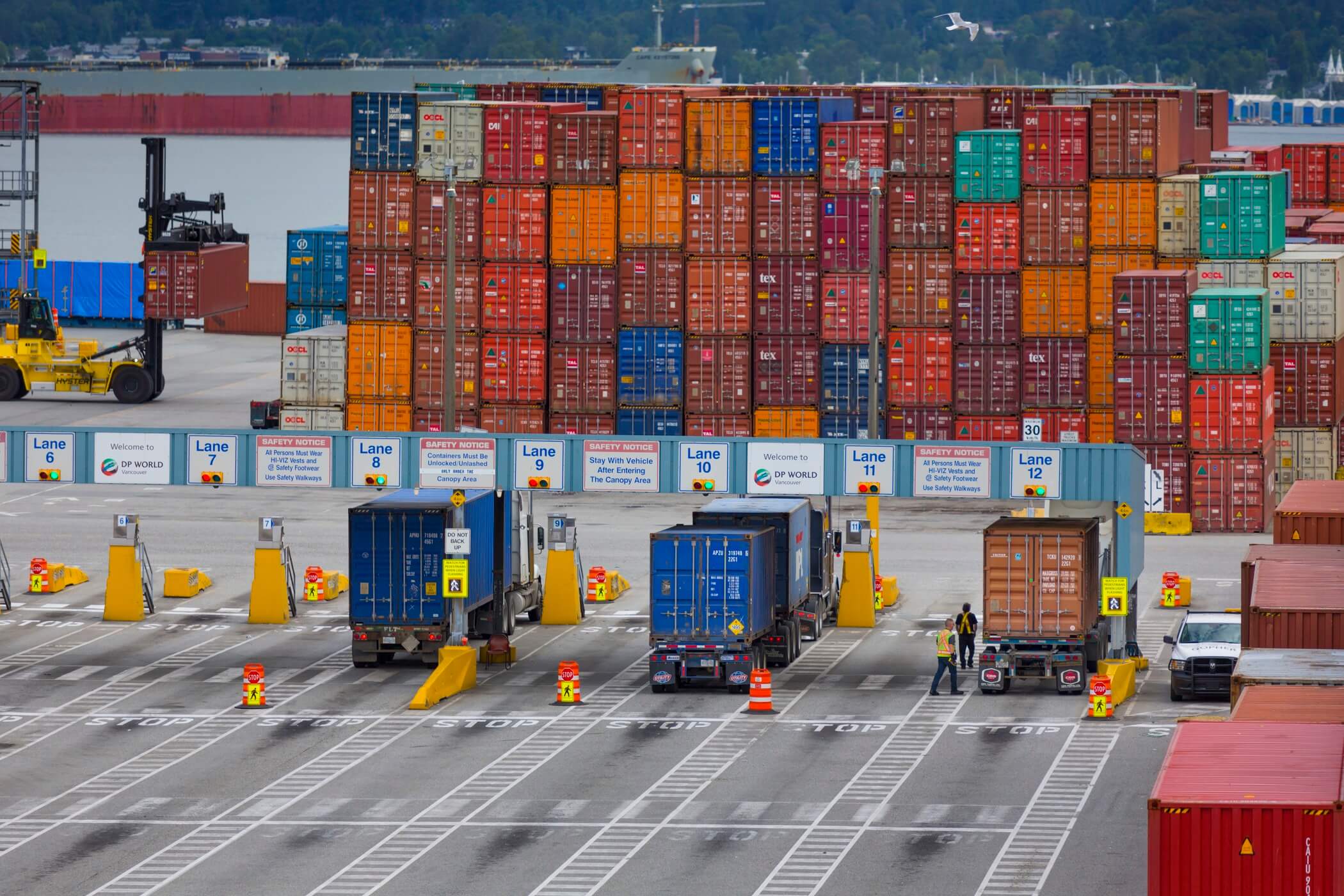 Various coloured shipping containers stacked in a shipping yard.
