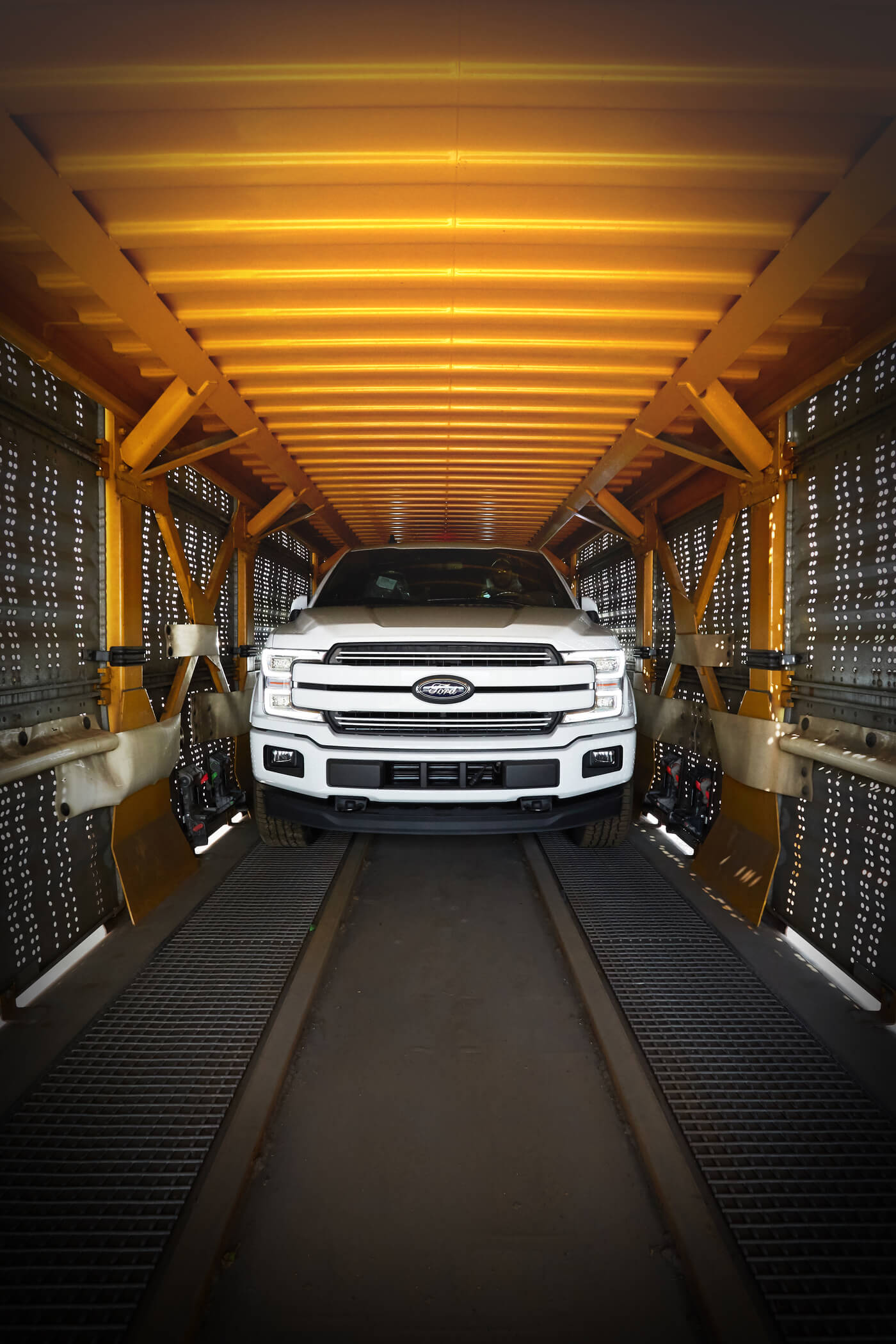 A black pickup truck going down a ramp off the back of a rail car.